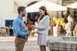 happy man presenting bouquet of roses to beautiful girlfriend on street