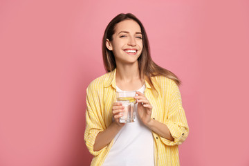 Sticker - Young woman with glass of lemon water on pink background