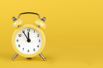 Yellow round alarm clock on the yellow background.