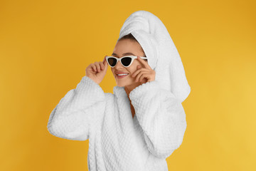 Sticker - Beautiful young woman in bathrobe and sunglasses on yellow background