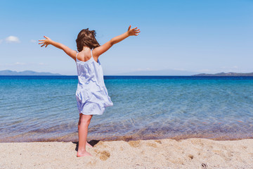 Cute little girl looking at sea on beautiful tropical beach. Summer, fun and vacations concept 