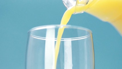 Poster - orange juice is poured into a glass on blue background