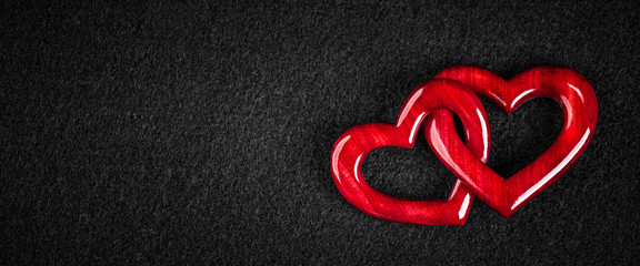 Wall Mural - two red wooden interlocking hearts on black felt background - valentine's day / marriage concept