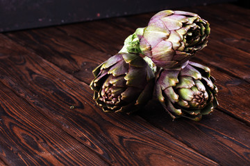 Wall Mural - artichokes on rustic background. fresh raw organic artichoke flower.