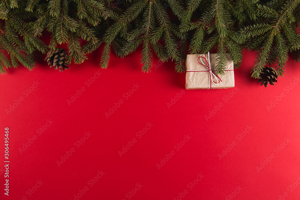 Christmas tree branches, gifts and pine cones on a red background, Christmas concept, greeting card copy space. - obrazy, fototapety, plakaty 