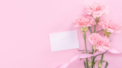 Beautiful, fresh elegant carnation flower bouquet with white greeting thanks gift card isolated on bright pink color background, top view, flat lay concept.