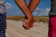 © Horacio Selva - Man hands linked on the beach. Love between men. Homosexual or same sex family concept.