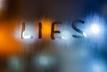 The Word Lies Written On Night Wet Window Glass Close-up With Bokeh Background