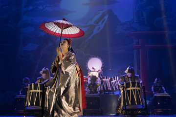 Wall Mural - Traditional Japanese performance. Actress in traditional kimono on the dark stage with umbrella and taiko drummers.