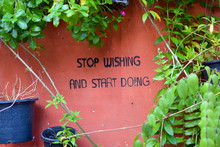 Stop Wishing And Start Doing Phrase Painted On Wall With Vines