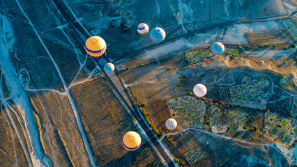 Aerial view of air balloon over fields, Cappadocia, Turkey. Aerial summer view from air balloon over road in Goreme, Cappadocia, Turkey. Aerial balloon over mountains at sunrise, Cappadocia, Turkey.