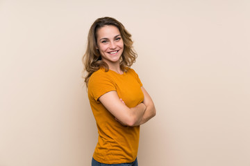 Wall Mural - Young blonde girl over isolated background with arms crossed and looking forward