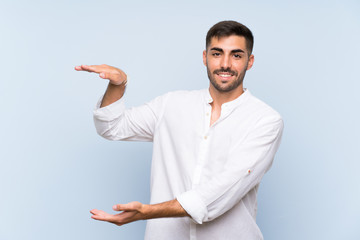 Wall Mural - Handsome man with beard over isolated blue background holding copyspace to insert an ad