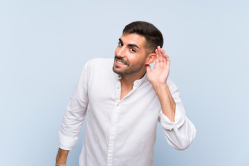 Wall Mural - Handsome man with beard over isolated blue background listening to something by putting hand on the ear