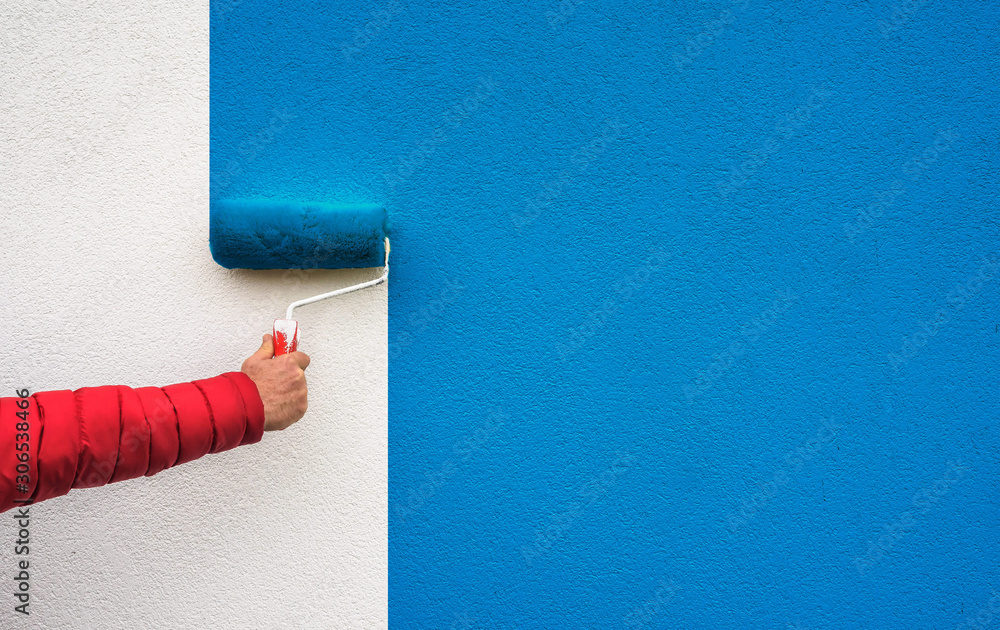 hand holds paint roller and painting a wall - obrazy, fototapety, plakaty 