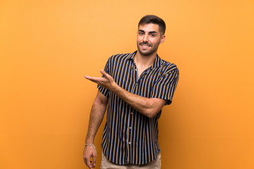 Handsome man with beard over isolated background presenting an idea while looking smiling towards