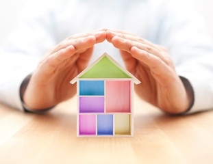 Canvas Print - Colorful wooden house protected by hands