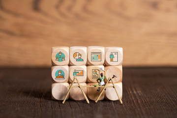 Wall Mural - little painter figure and business icons on cubes in front of wooden background