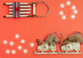 christmas flat lay with natural decoration snowflakes wooden Christmas tree decorations: sleigh ice skates on red backgound with the area for the text