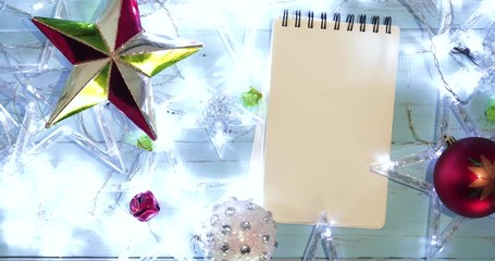 Wall Mural - Flat lay glowing stars with ornaments Christmas and empty notepad on the wooden table. Shot in 4k resolution