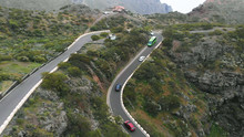 Aerial View. Narrow Serpentine, In Which It Is Difficult To Drive Cars Towards Each Other. The Road Along The Mountain Range, Different Cars, A Tropical Climate.