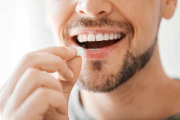 Man taking medicine at home, closeup