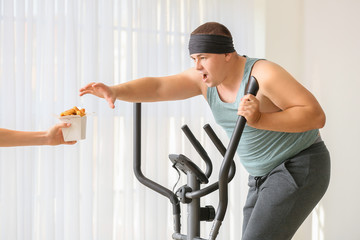 Sticker - Hand with junk food and overweight man training at home