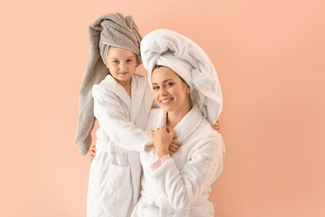 Canvas Print - Portrait of happy mother and daughter in bathrobes on color background