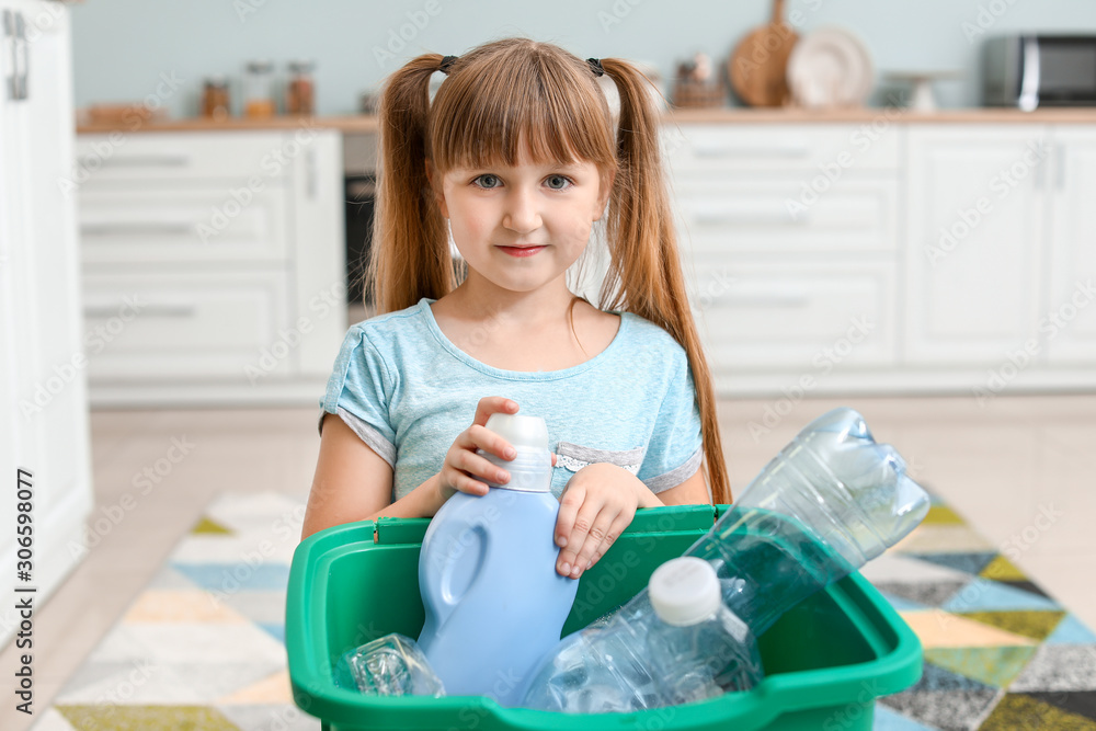 Little girl and container with trash in kitchen. Concept of recycling