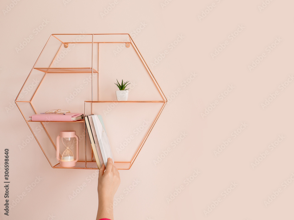 Woman taking book from shelf on color wall