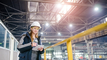 Young female technician in uniform, protective eyeglasses and helmet