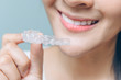© Varangkana - close up mouth of Woman holding orthodontic silicone. Mobile orthodontic appliance for dental correction.