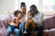 © fizkes - Happy biracial family with kids relax on cozy sofa