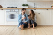 © fizkes - Happy affectionate couple talking drinking wine sit on kitchen floor