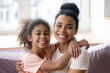 © fizkes - Portrait of smiling biracial mom and daughter cuddling at home