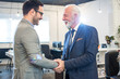 © Bojan - Senior executive shaking hands with young employee at office
