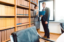 Lawyers in library of law firm discussing strategy in a case holding file