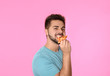 © New Africa - Handsome man eating pizza on pink background
