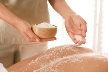 Wall Mural - Young woman having body scrubbing procedure with sea salt in spa salon, closeup