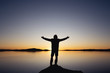 © cppzone - Silhouette with raised arms against sunset lake