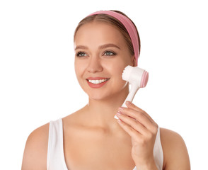 Poster - Young woman washing face with cleansing brush on white background. Cosmetic product