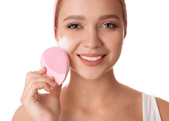 Poster - Young woman washing face with brush and cleansing foam on white background. Cosmetic products