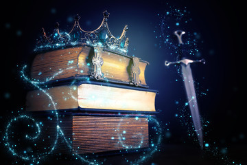 Poster - low key image of beautiful queen/king crown over antique book and sword. fantasy medieval period. Selective focus