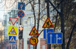 © Евгений Медведев - a large number of road signs, symbols of detours, road repairs near the traffic light with a pedestrian crossing on the background of city buildings and tree branches