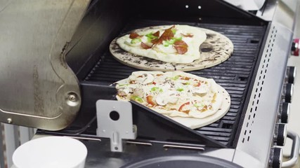 Sticker - Preparing individual grilled pizzas on an outdoor gas grill.