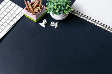 Top view workspace with white computer keyboard, pencil, houes and blank page of notebook.