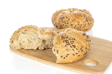 Group of one whole two halves of sesame kaiser roll on bamboo cutting board isolated on white background