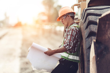 Architect holding rolled up blueprints at construction site