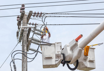 Canvas Print - Electrician repairing wire of the power line on electricity power pole  with bucket hydraulic lifting platform