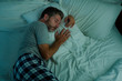 © TheVisualsYouNeed - domestic lifestyle high angle portrait of young attractive and relaxed man sleeping alone on bed at home lying tranquil at night in dim light resting and dreaming